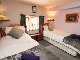 A bedroom with two beds and a window at Tethera Cottage in Bampton, Cumbria