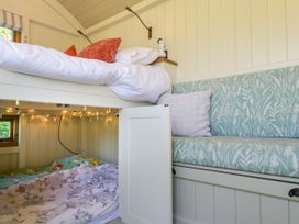 A bedroom with a bunk bed and a built-in cushioned seating area with pillows at Hazel in South Leigh near Witney