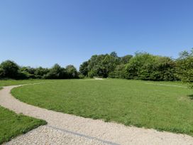 An outdoor grassy area with a gravel circular pathway and trees in the background at Hazel South Leigh near Witney