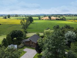 A view of fields and trees with a house in the foreground at Cedrus Lodge in Skelton near Penrith