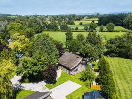 A view of a building surrounded by trees and grass at Larch Lodge in Skelton near Penrith
