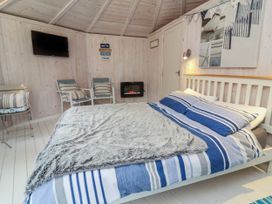 A bedroom with a bed with blue striped bedding two chairs and a wall-mounted television at Welcombe Mouth near Hartland