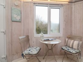 A small room with a round table and two chairs with cushions near a window at Welcombe Mouth near Hartland