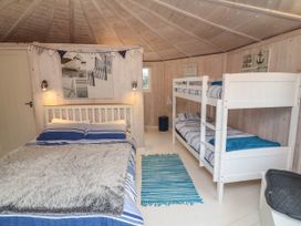 A bedroom with a double bed and bunk beds with blue and white bedding a striped rug and wall decorations at Welcombe Mouth near Hartland