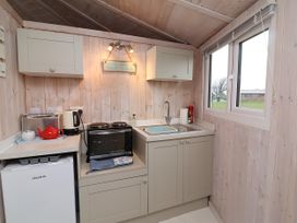 A small kitchen area with a sink toaster kettle oven and mini fridge near a window at Welcombe Mouth near Hartland
