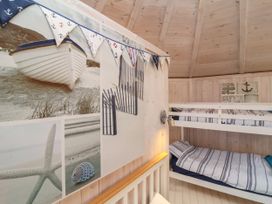 A bedroom with wooden walls and bunk beds decorated with nautical-themed pictures and bunting at Welcombe Mouth near Hartland