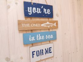 A wooden wall with four wooden signs displaying the text you're the only fish in the sea for me Welcombe Mouth near Hartland