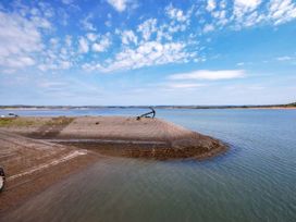 A shoreline with an old anchor on a paved mound near calm water under a partly cloudy sky at Welcombe Mouth near Hartland