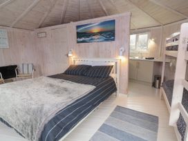 A bedroom with a double bed two bunk beds a chair a rug and a kitchenette at Sandy Bay near Hartland