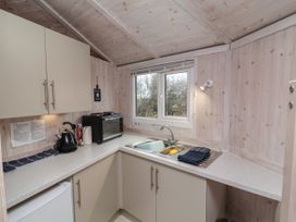 A small kitchen with a sink a toaster kettle and cupboards near a window at Sandy Bay near Hartland