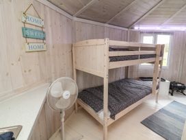 A bunk bed with black and white bedding in a wooden room with a standing fan and a Home Sweet Home sign at Sandy Bay near Hartland