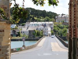 A narrow bridge over water leading to buildings and trees with signs on the bridge near Hartland
