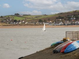 A body of water with a sailboat near a shore with houses and hills at Sandy Bay near Hartland