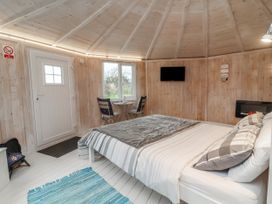A bedroom with a bed table chairs a television and a window at Blackpool Mill near Hartland
