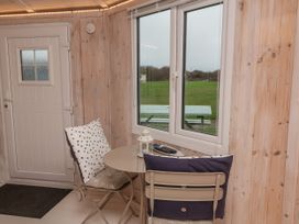 A small dining area with two chairs and a round table by a window overlooking a green field at Blackpool Mill near Hartland