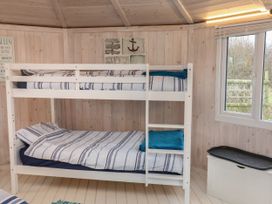 A bedroom with white bunk beds near a window at Barley Bay near Hartland