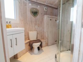 A bathroom with a toilet a shower a white cabinet and a heart shaped mirror at Barley Bay near Hartland