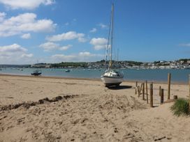A sandy beach with a boat on the shore and several boats in the water at Barley Bay near Hartland
