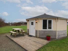 A small octagonal wooden cabin with a picnic table on a wooden deck outside at Duck Pool near Hartland