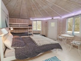 A bedroom with a double bed and bunk beds along with a small round table and two chairs at Duck Pool near Hartland