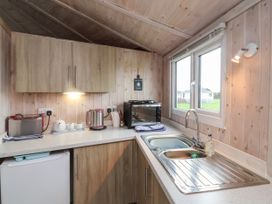 A kitchen with a sink toaster kettle and oven near a window at Duck Pool near Hartland