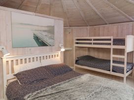 A bedroom with a double bed and bunk beds in a wooden room at Duck Pool near Hartland
