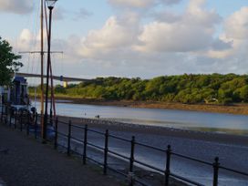 A riverside walkway with boats docked along the side and a bridge in the background at Duck Pool near Hartland