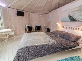 A bedroom with a bed a small round table with two chairs two armchairs and a wall-mounted TV at Spekes Mill near Hartland
