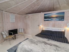 A bedroom with a bed two chairs a door and wall art at Berry Bay near Hartland