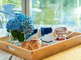 A tray with croissants, flowers, mugs, jam, and strawberries at Pentire St Minver