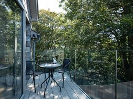 An outdoor deck with a table and chairs at Pentire in St Minver