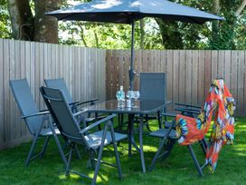 A garden with a table and chairs under an umbrella at Pentire St Minver