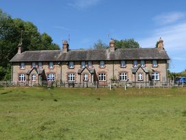 A row of stone cottages with chimneys and fenced front gardens in a rural area at 3 Railway Cottages in Long Marton near Appleby-In-Westmorland