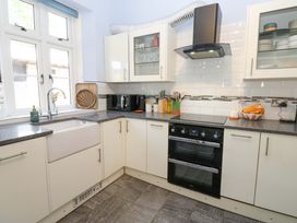 A kitchen with white cabinets a double oven a sink under a window and countertop appliances at 3 Railway Cottages Long Marton near Appleby-In-Westmorland