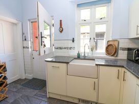 A kitchen with a white farmhouse sink under a window and a door to the outside at 3 Railway Cottages in Long Marton near Appleby-In-Westmorland
