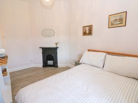 A bedroom with a bed striped bedding a small fireplace a mirror and two paintings at 3 Railway Cottages in Long Marton near Appleby-In-Westmorland