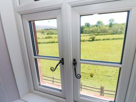 A view of green fields and trees through a white framed double window with black handles at 3 Railway Cottages in Long Marton near Appleby-In-Westmorland