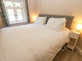 A bedroom with a double bed white bedding bedside tables with lamps and a window with floral curtains at 3 Railway Cottages in Long Marton near Appleby-In-Westmorland