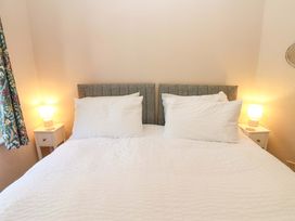 A bedroom with a double bed with white bedding and gray headboards with bedside tables and lamps in 3 Railway Cottages Long Marton near Appleby-In-Westmorland