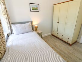 A bedroom with a single bed striped bedding a nightstand with a lamp a wardrobe and a framed picture on the wall at 3 Railway Cottages Long Marton near Appleby-In-Westmorland