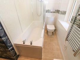 A bathroom with a bathtub shower combination a toilet a window and a towel radiator at 3 Railway Cottages Long Marton near Appleby-In-Westmorland