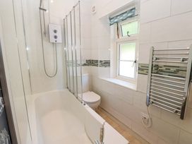 A bathroom with a bathtub shower combination toilet window with a fish patterned blind and a heated towel rail at 3 Railway Cottages in Long Marton near Appleby-In-Westmorland