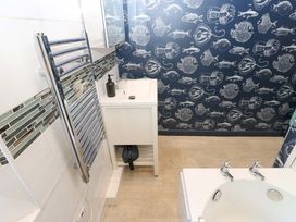 A bathroom with a white sink cabinet a chrome towel rail and marine life wallpaper at 3 Railway Cottages Long Marton near Appleby-In-Westmorland