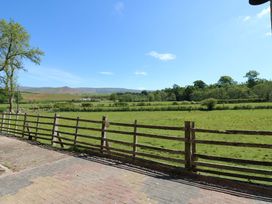 A fenced grass field with trees and hills in the background at 3 Railway Cottages Long Marton near Appleby-In-Westmorland