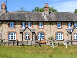 A stone brick terraced house with white framed windows and a wooden fence in front at 3 Railway Cottages in Long Marton near Appleby-In-Westmorland