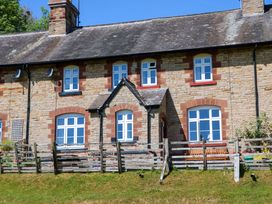 The exterior of a stone cottage with white framed windows and a wooden fence in front at 3 Railway Cottages in Long Marton near Appleby-In-Westmorland