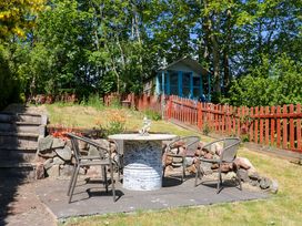 A garden patio with a round table and four chairs near a red wooden fence and a small shed at 3 Railway Cottages in Long Marton near Appleby-In-Westmorland