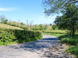 A country road with hedges and trees on both sides under a clear blue sky at 3 Railway Cottages in Long Marton near Appleby-In-Westmorland