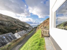 An outdoor view showing a pathway and houses near the sea at Little Ruffo in Trebarwith near Tintagel