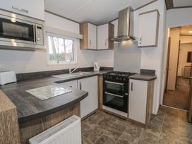 A kitchen with a sink, cooker, and microwave at Woodlands Gold (WO 41) in Ruthin